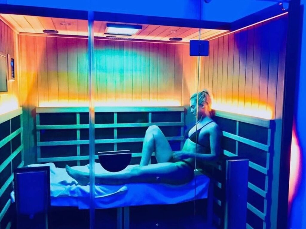 woman sitting in infrared sauna using chromotherapy